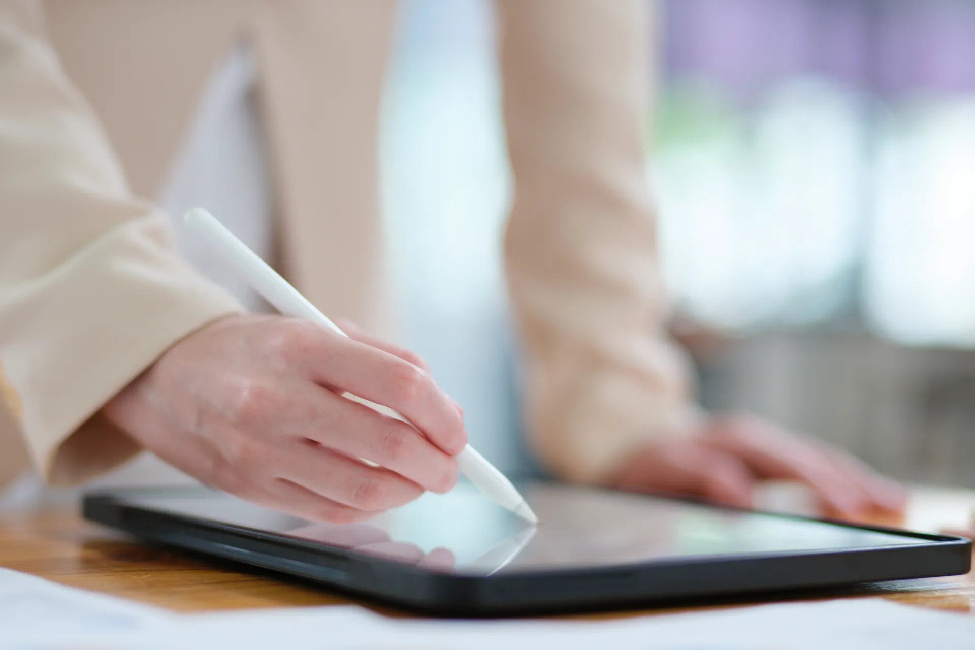 Manos usando un lápiz digital sobre una tableta en una mesa de trabajo