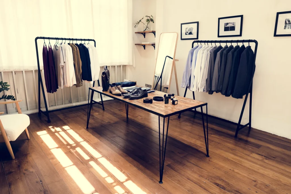Tienda de ropa luminosa con percheros y mesa expositora