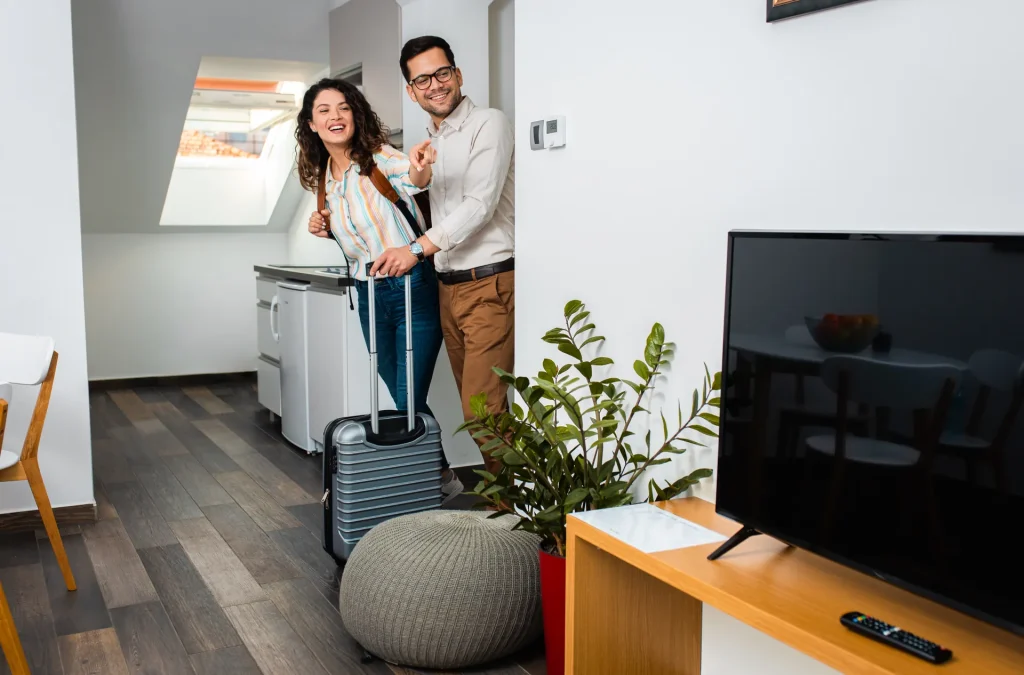 Pareja llegando con maletas a un apartamento luminoso