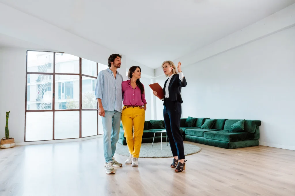 Agente inmobiliaria enseñando un piso vacío a una pareja