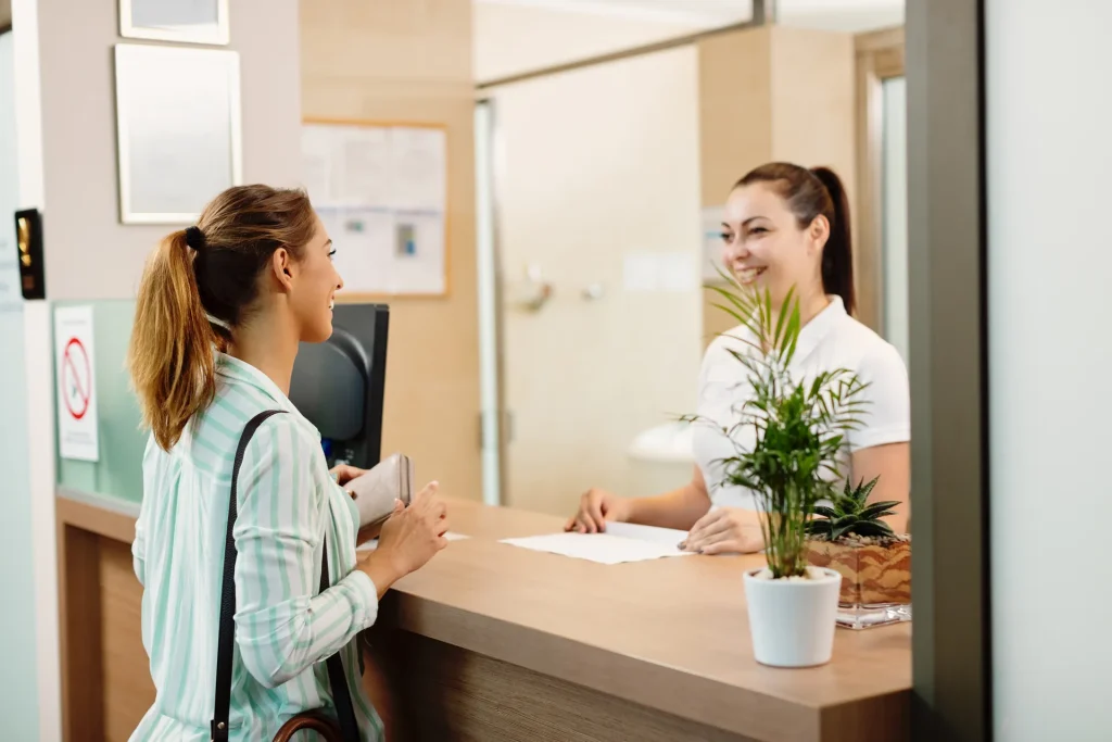 Recepcionista atendiendo a una joven en el mostrador de recepción
