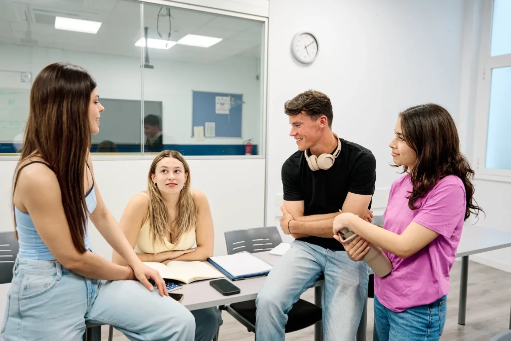 Grupo de estudiantes jóvenes conversando alrededor de una mesa