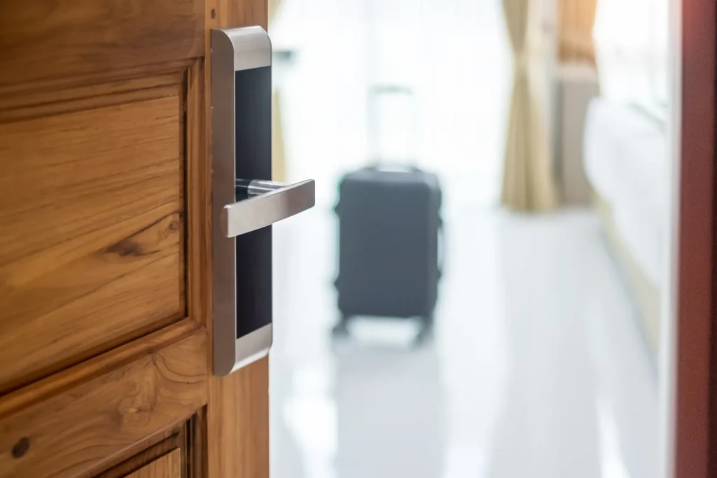 Puerta de habitación con cerradura electrónica y una maleta al fondo