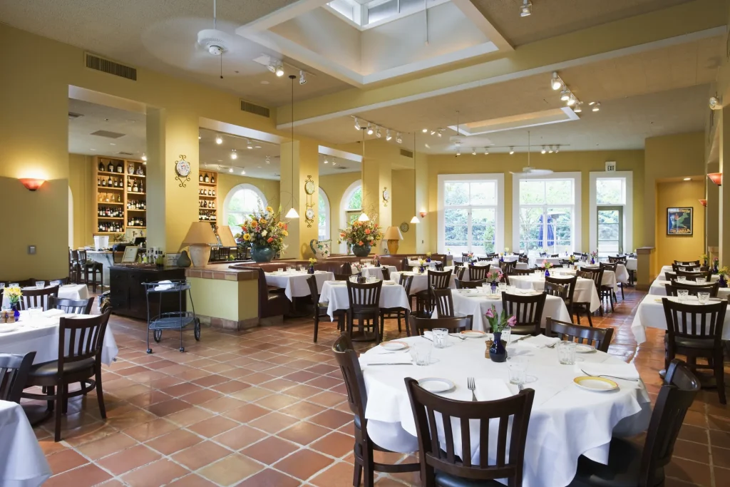 Comedor de restaurante con mesas vestidas y sillas de madera