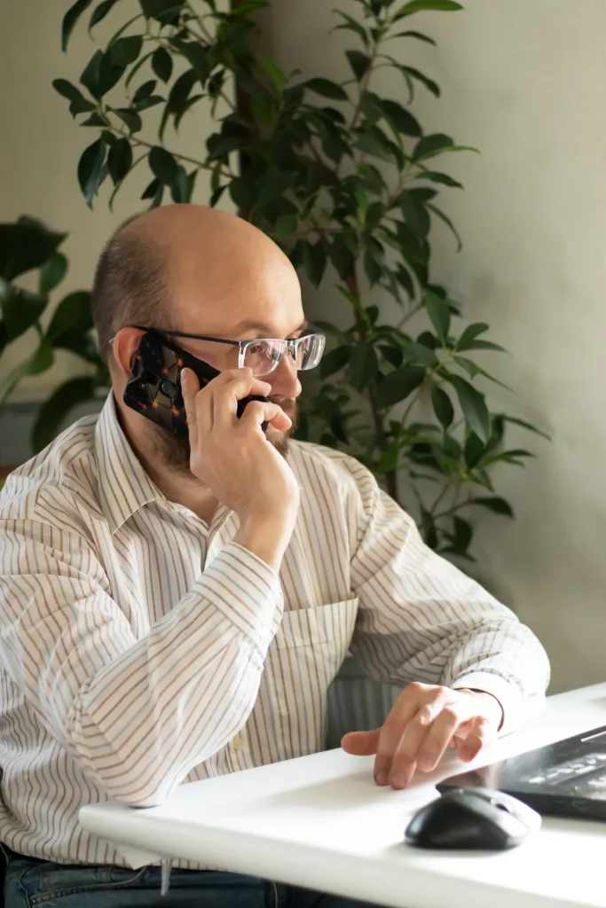 Profesional hablando por teléfono en su mesa de trabajo junto a una planta