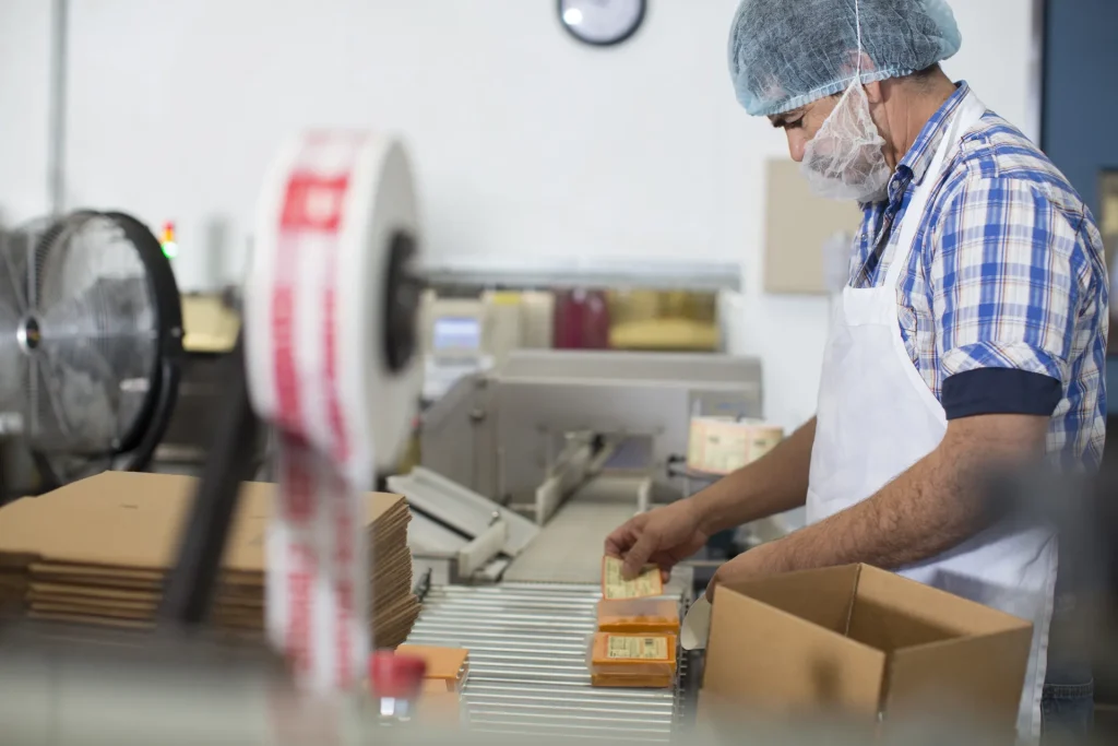 Operario empaquetando productos junto a una línea automatizada
