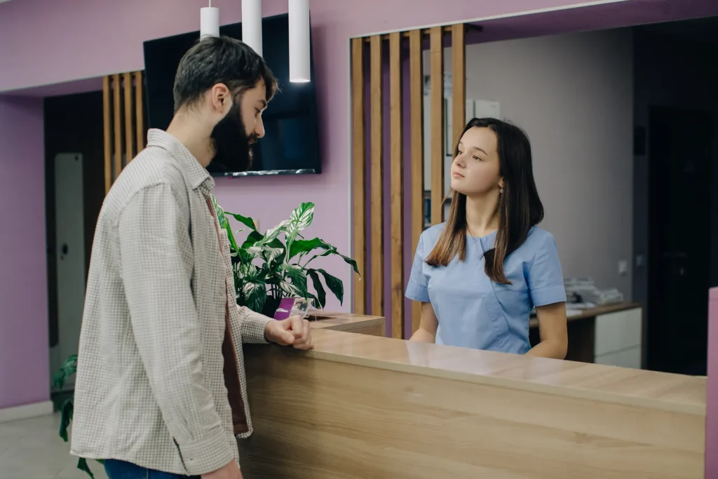 Recepcionista atendiendo a un paciente en el mostrador de una clínica