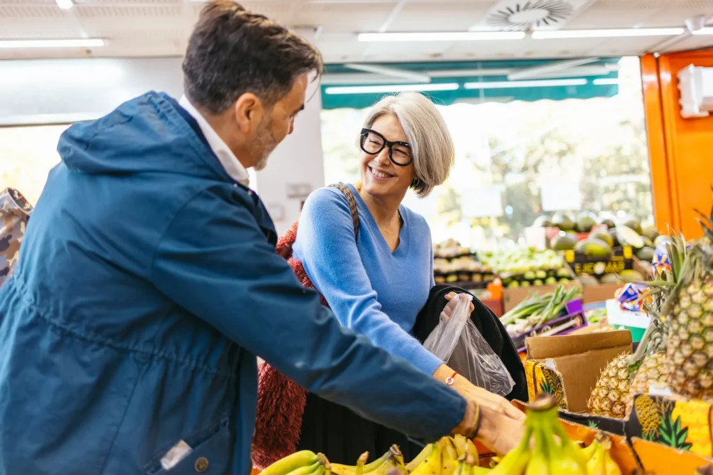Pareja de personas mayores comprando fruta en un mercado