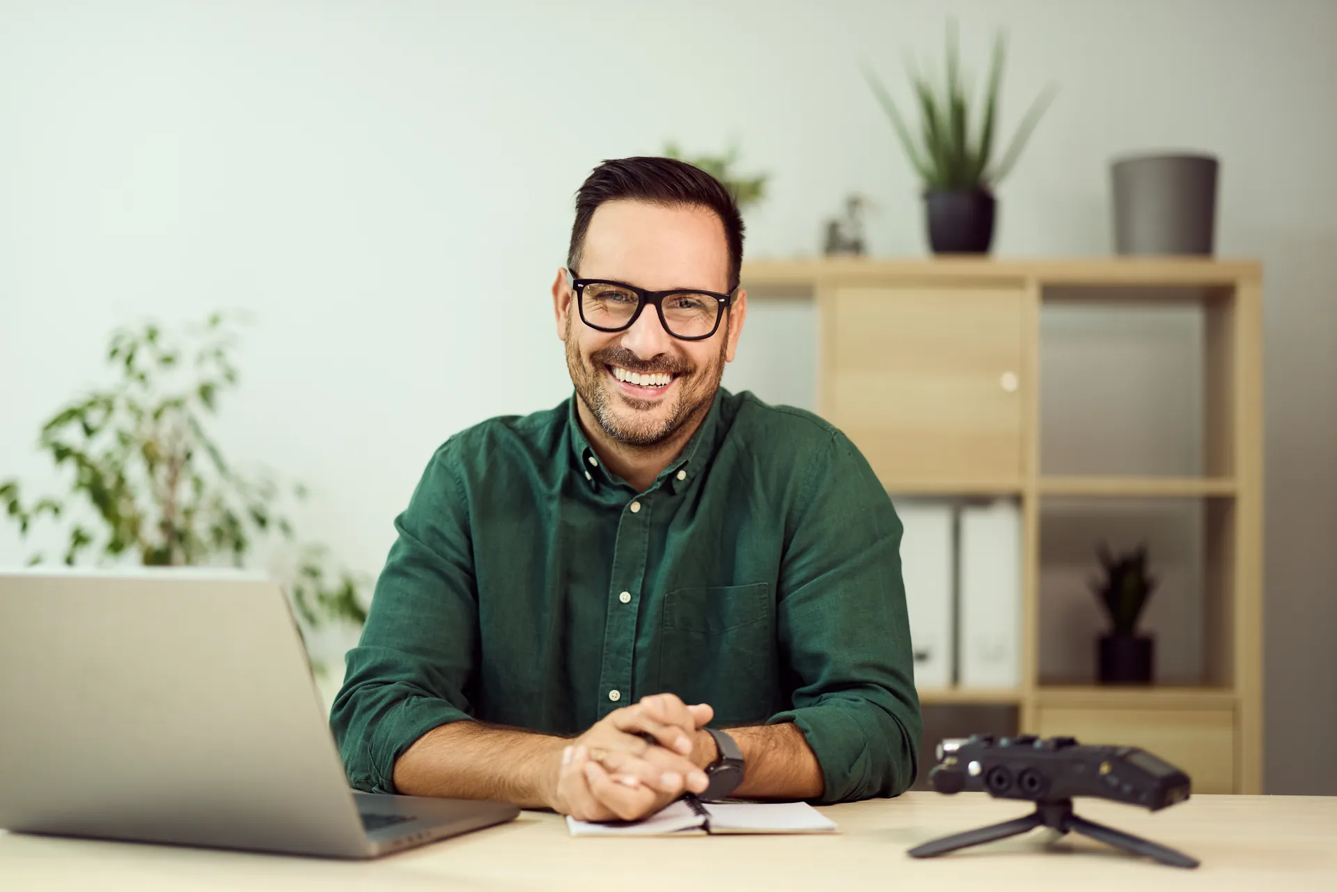 Profesional sonriente sentado ante su portátil en una oficina luminosa