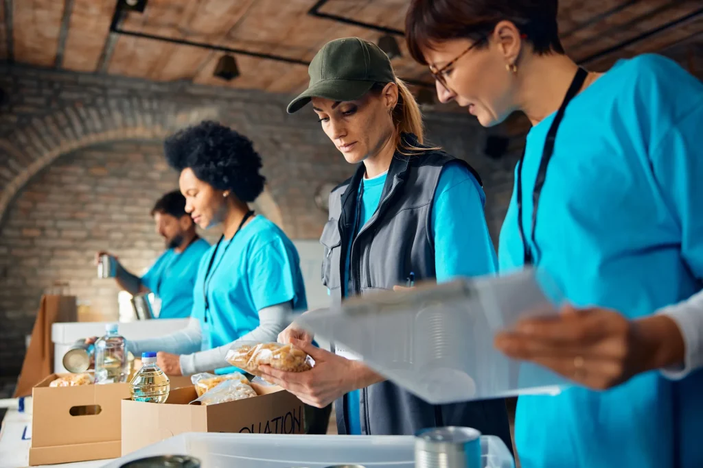 Voluntarias organizando donaciones de alimentos con una lista en la mano