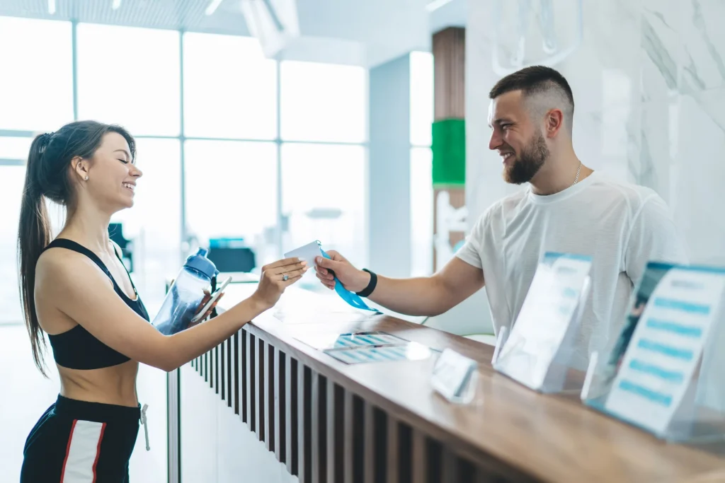 Clienta entregando su tarjeta en la recepción de un gimnasio