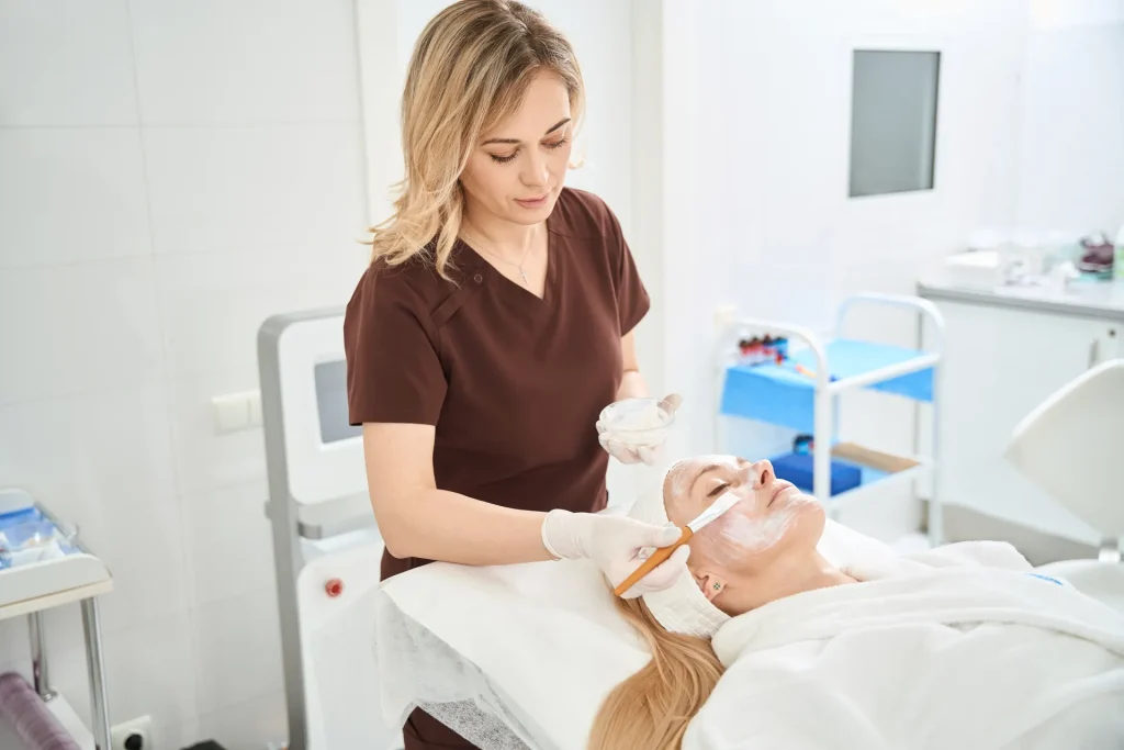 Esteticista aplicando una mascarilla facial a una clienta en un centro de estética