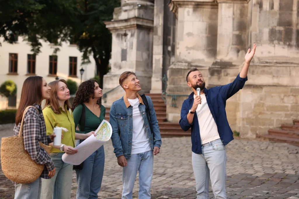 Guía con micrófono explicando un monumento a un pequeño grupo de visitantes